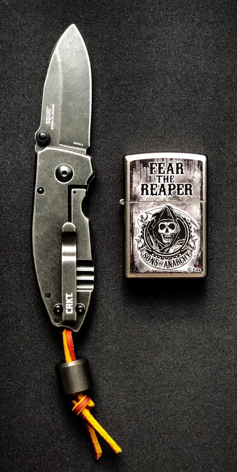 CRKT Squid folding knife and Sons of Anarchy Zippo lighter with Fear the Reaper logo on a dark textured background.