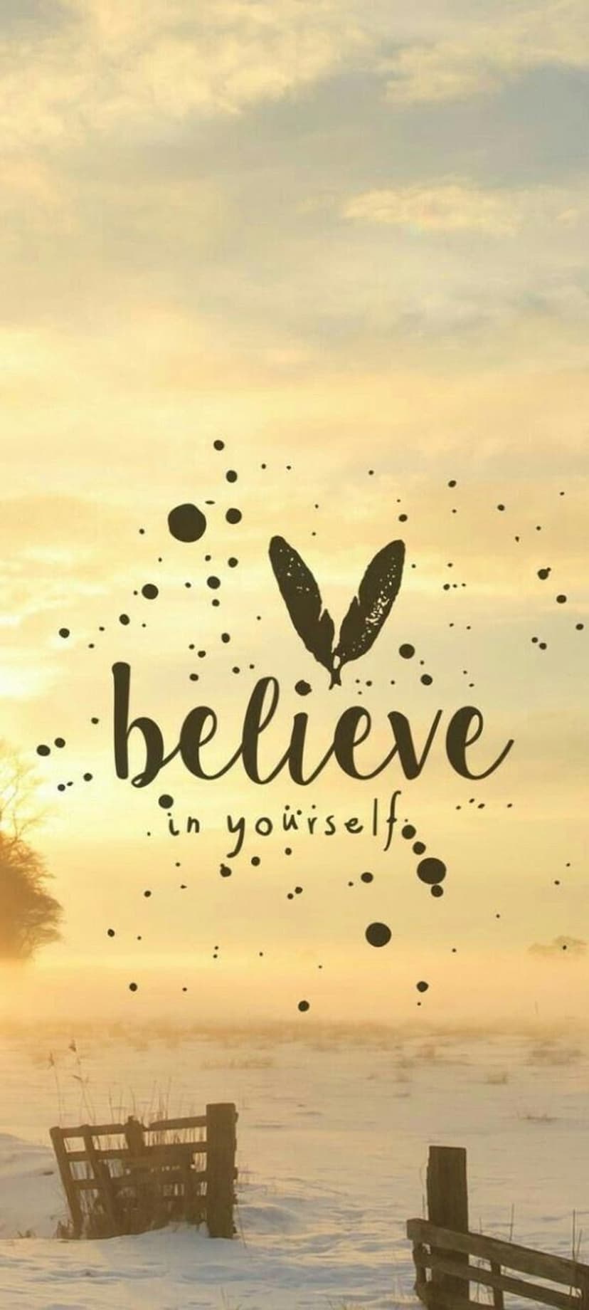 Believe in yourself text centered over a snow-covered field with wooden fence posts during a golden sunrise.