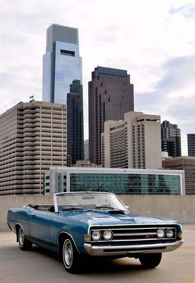 Blue Convertible Classic Car with City Skyline Background