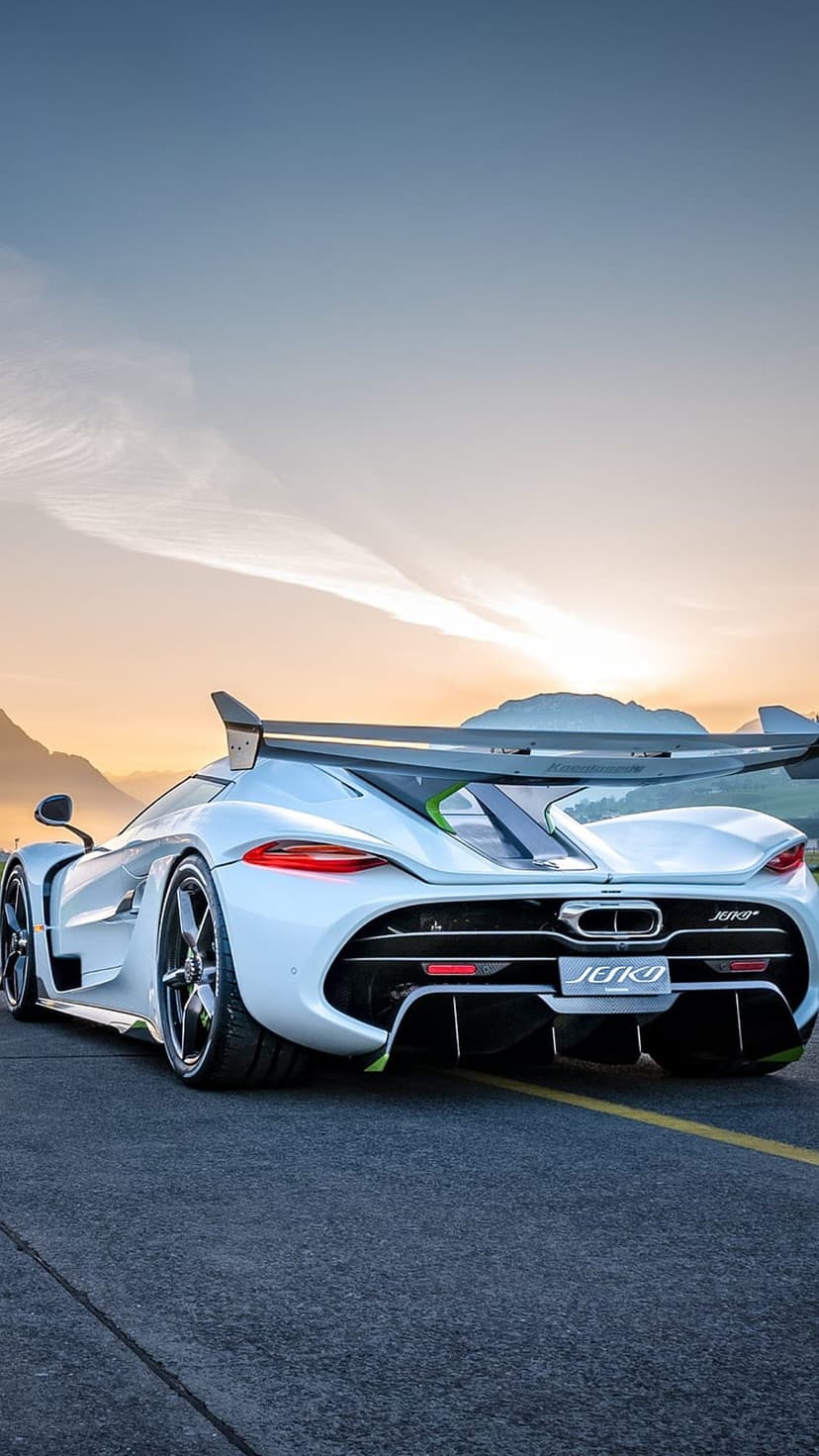 White Koenigsegg Jesko Absolut hypercar parked on an asphalt mountain road during a vibrant golden hour sunset.