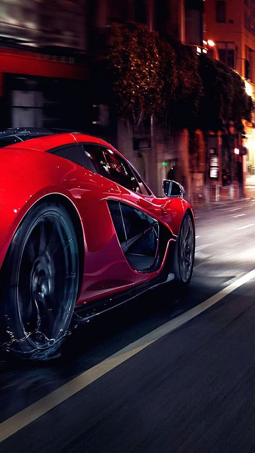 Red hypercar accelerating on a wet city street at night with motion blur and neon reflections on its chassis.