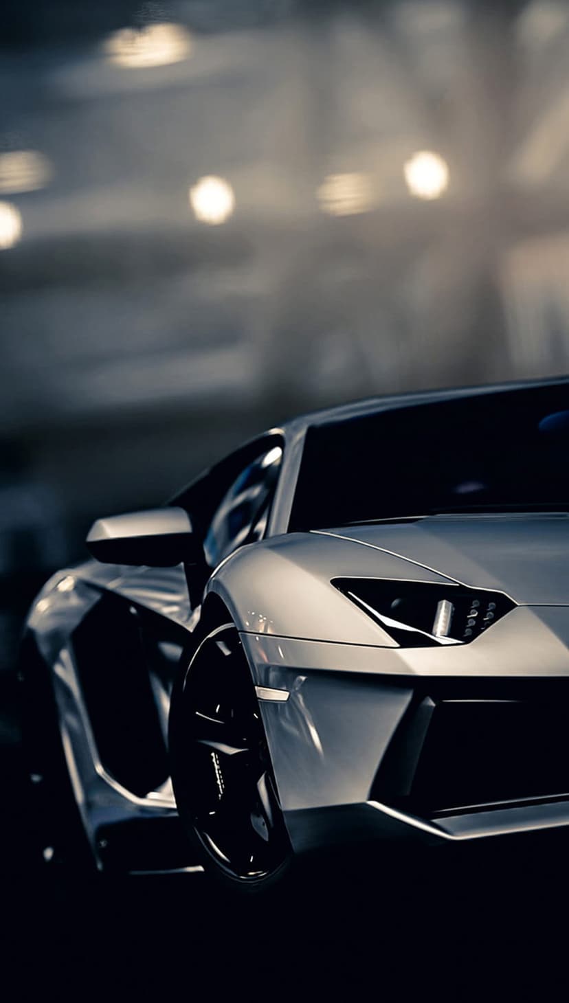 Silver Lamborghini Aventador headlight and black alloy wheel featuring sharp lines and bokeh background lights.