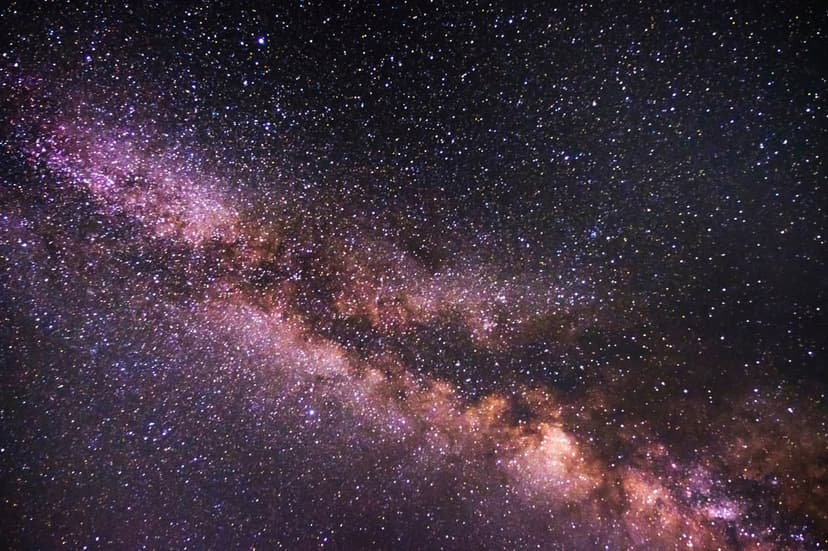 Milky Way galaxy core with dense purple star clusters and dark cosmic dust clouds stretching diagonally.