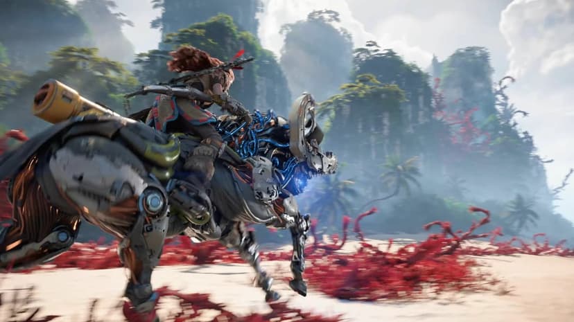 Aloy riding a robotic mount across a beach with red plants and towering green cliffs under a bright sky.