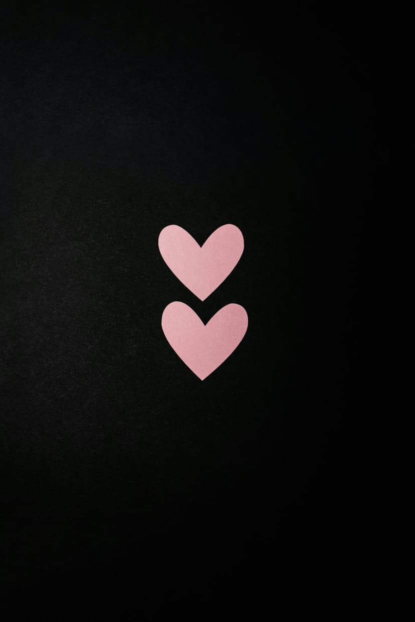 Two pastel pink paper hearts stacked vertically against a dark, textured black background with sharp contrast.