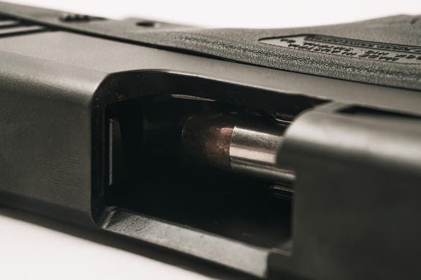 Brass bullet partially seated inside a black handgun chamber with detailed metallic textures and matte finish.