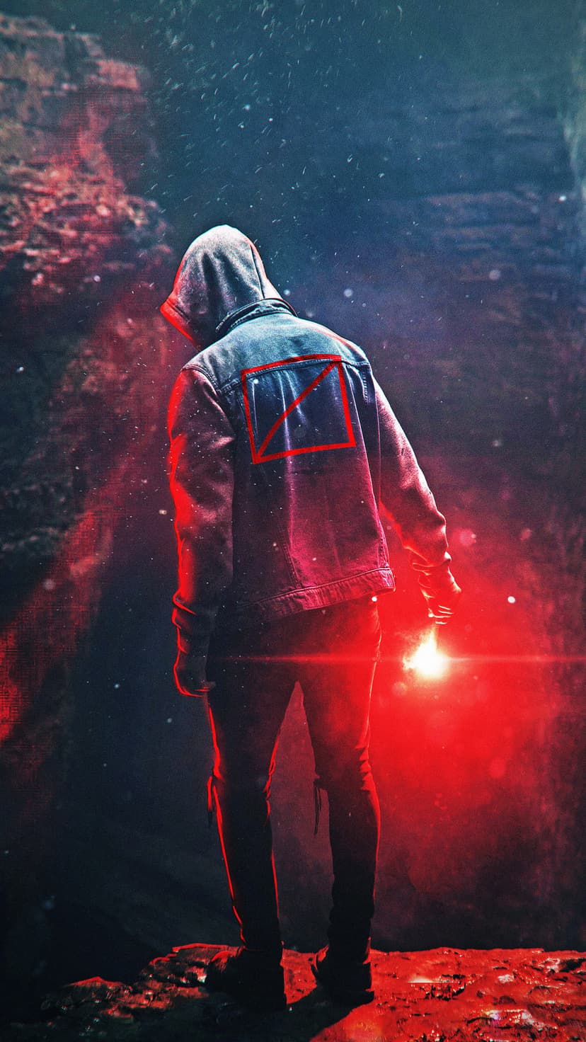 Hooded person from behind holding a glowing red flare in a dark cave, casting light on a red triangle logo.