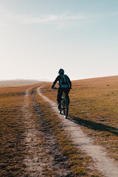Mountain biker rides on a dusty trail through golden fields
