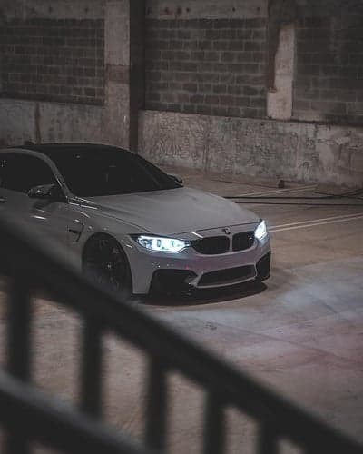 White BMW M4 Sports Car Phone Wallpaper In Dark Garage