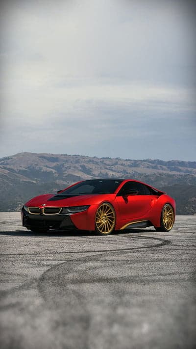 Red BMW i8 with gold rims on textured ground