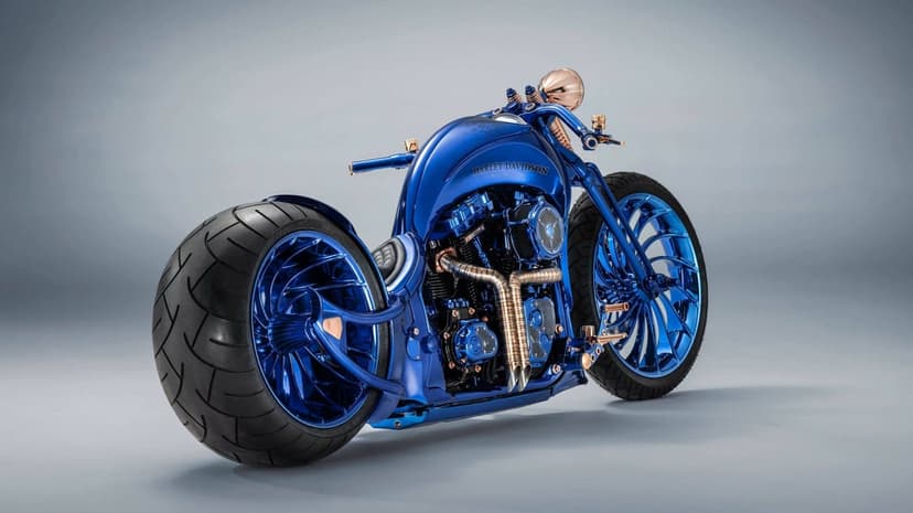 Electric blue custom Harley-Davidson motorcycle with rose gold engine parts and large tires in a studio setting.