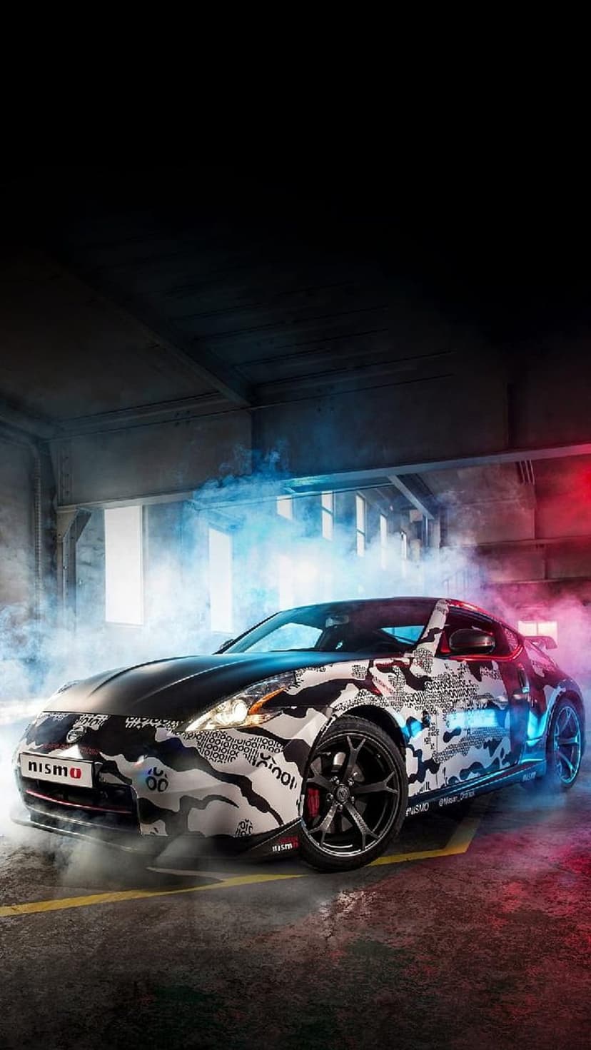 Nissan 370Z Nismo sports car with a camouflage wrap surrounded by swirling red and blue smoke on a dark background.