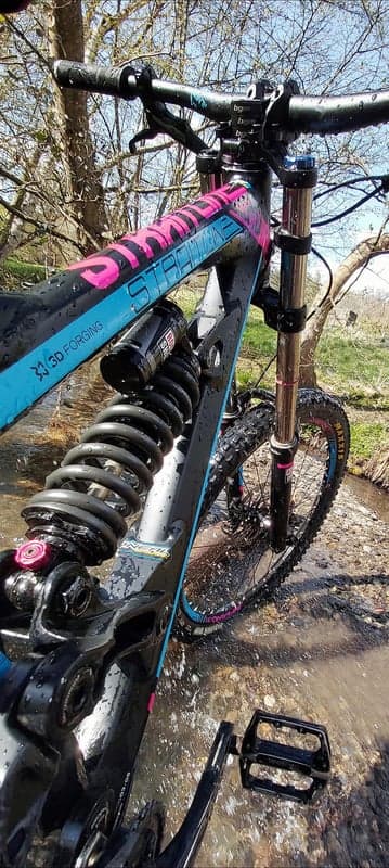 Downhill mountain bike in water with pink and blue accents