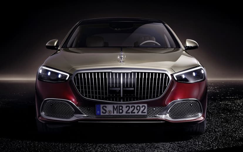 Front view of a two-tone gold and red Mercedes-Maybach luxury sedan with a chrome grille in a dark studio.