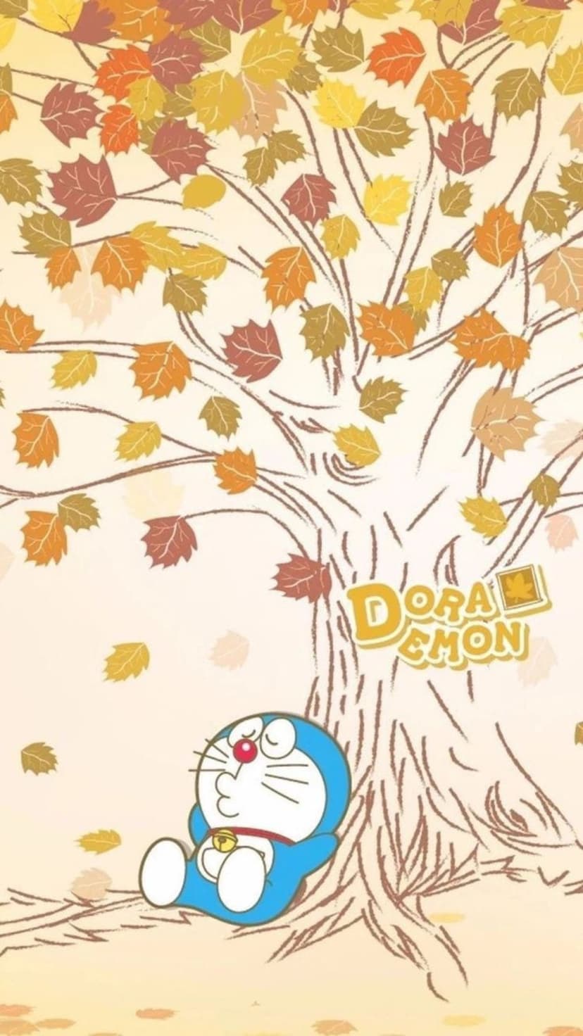Doraemon sits calmly under a large tree with bright orange falling leaves and a warm seasonal background glow.