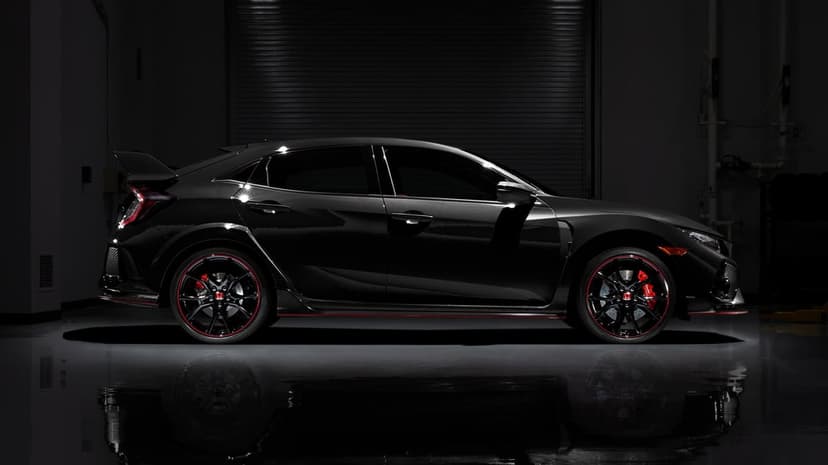 Black Honda Civic Type R side profile in a dark garage with red wheel accents and reflective floor surface.