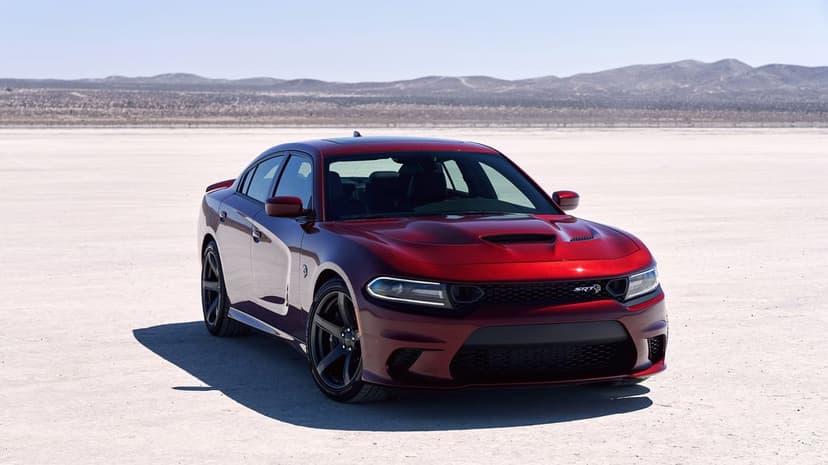 Red Dodge Charger SRT Hellcat parked on a wide white desert dry lake bed under a clear, bright blue sky.