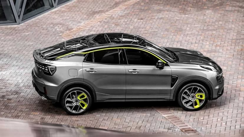 Grey crossover SUV with neon green wheels and roof accents parked on a stone paved courtyard from a high angle.