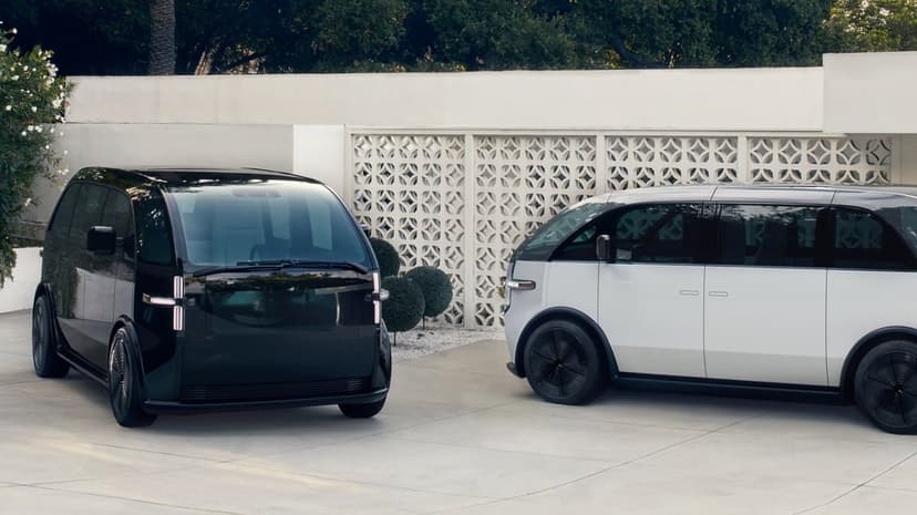 Black and silver futuristic electric vans parked against a white geometric lattice wall in daylight.