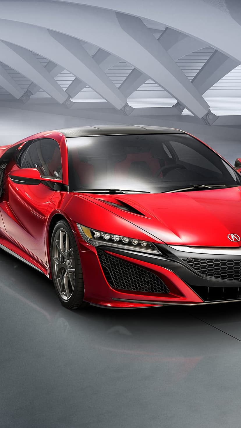 Red Acura NSX supercar with sharp front grille and LED headlights parked in a minimalist gray architectural garage.