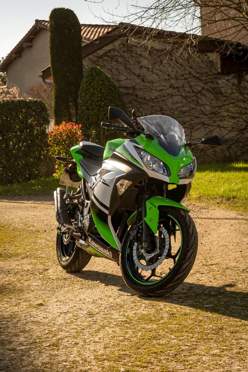 Lime green Kawasaki Ninja sportbike parked on a dirt path next to a building wall covered in thick green ivy.