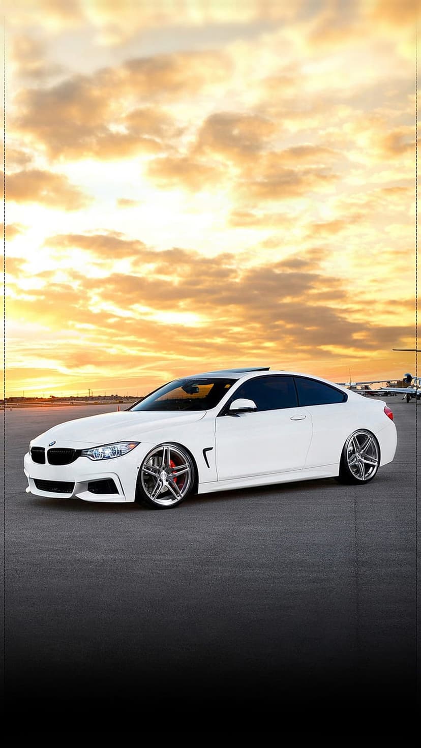 White BMW coupe parked on a sunset tarmac with an airplane under a golden sky for mobile phone screens.
