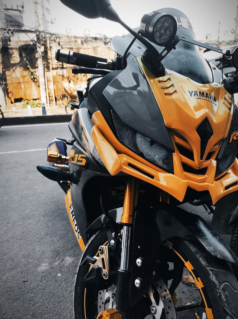 Yamaha R15 motorcycle with yellow fairings and black accents highlighting its sharp headlights and gold forks.