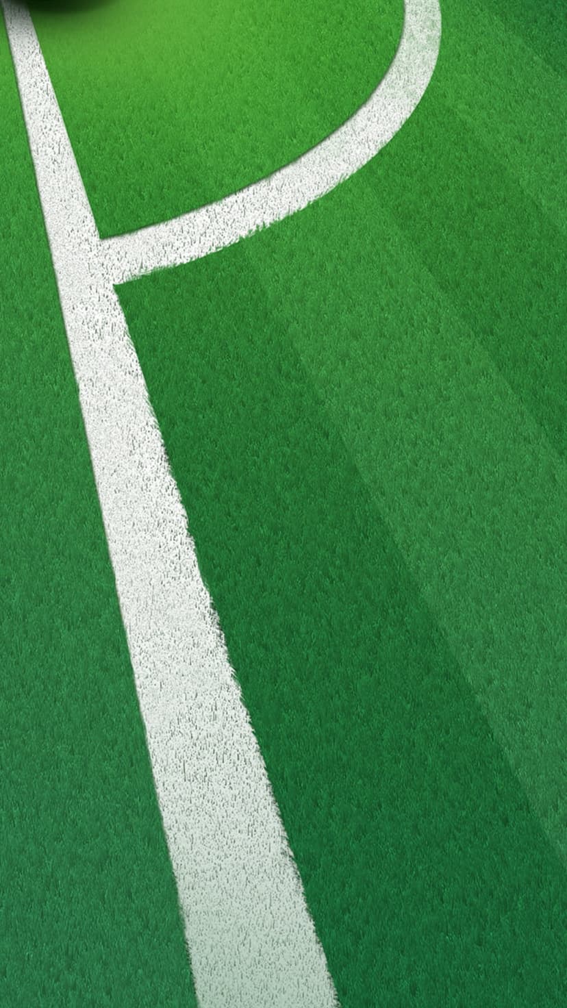 Green artificial turf blades meet a sharp white boundary line in a close-up view of a professional soccer pitch.
