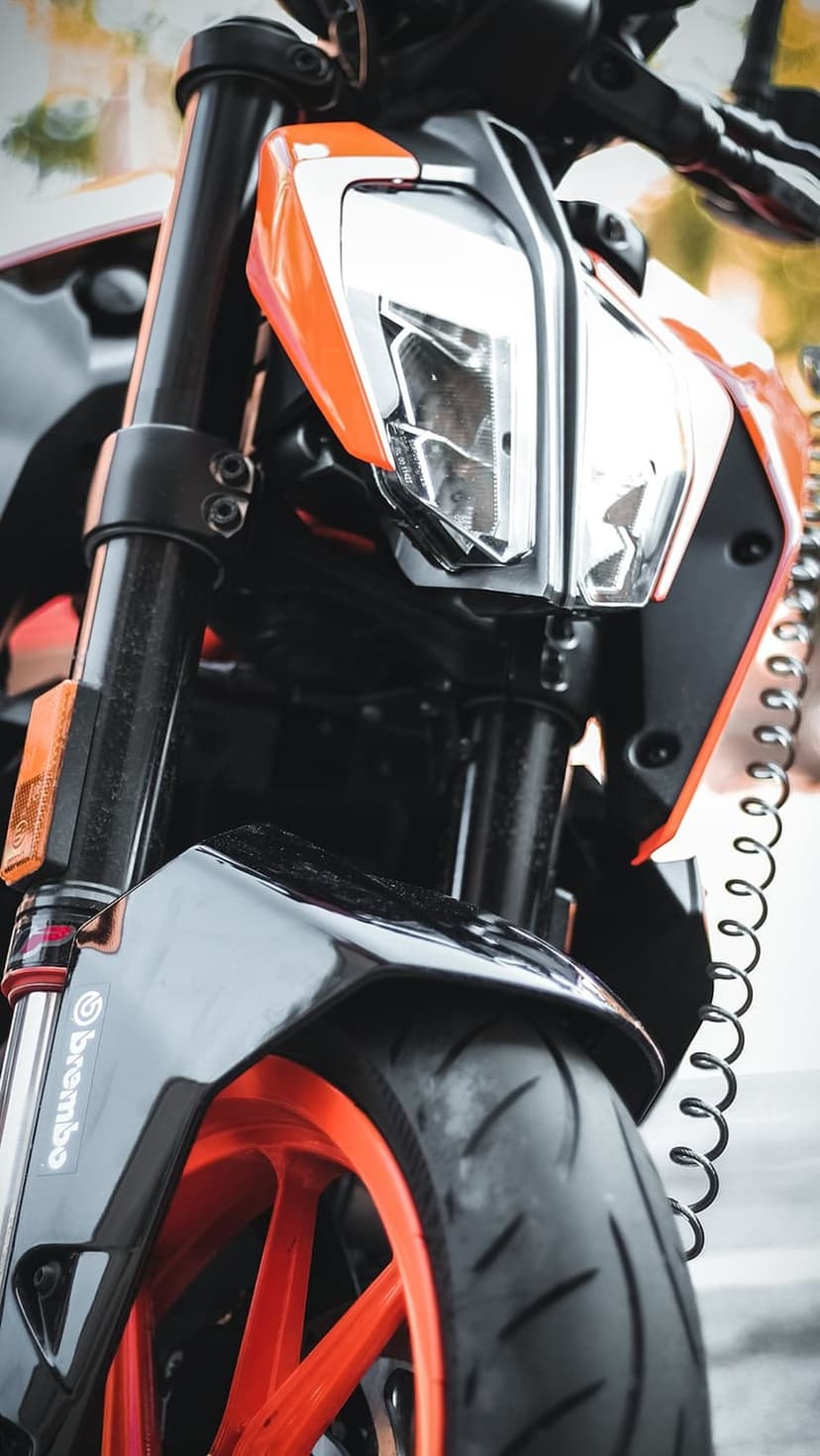 KTM motorcycle front forks and orange rim feature a sharp headlight assembly and a coiled security cable.