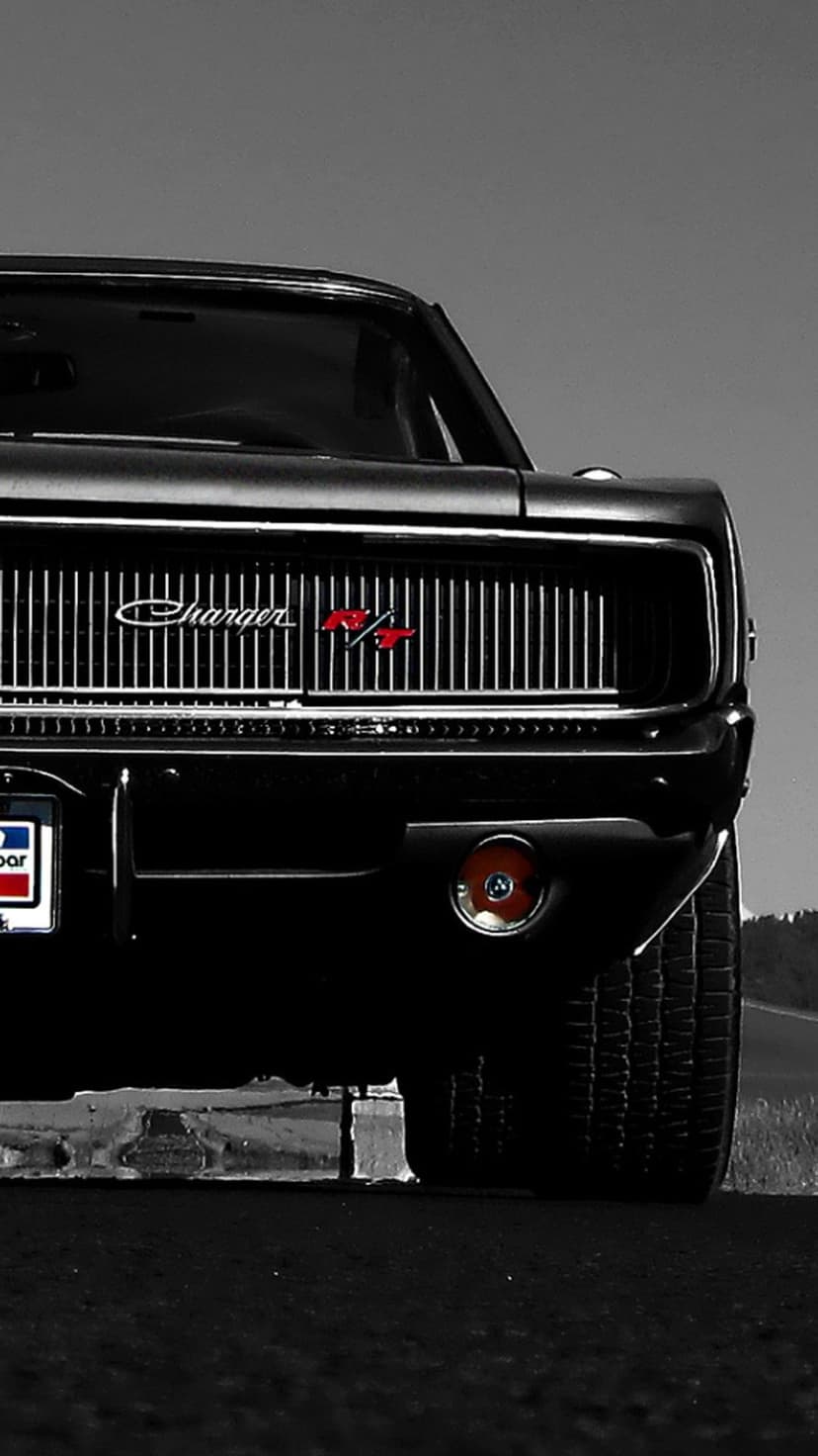 Front view of a black Dodge Charger R/T with a silver grille, red R/T badge, and low-angle tire detail.