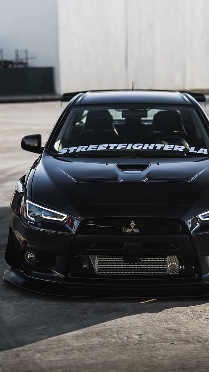 Mitsubishi Lancer Evolution X with a Streetfighter LA banner, LED headlights, and an exposed intercooler.