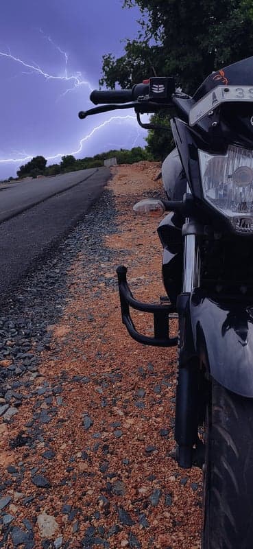 Motorcycle parked on roadside during lightning storm