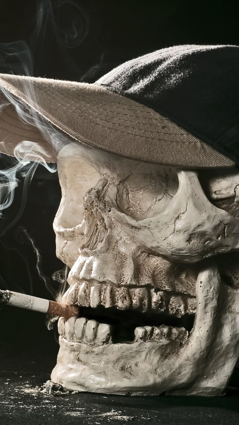 Skull in a peaked cap smoking a cigarette with thick vapor clouds drifting against a solid black background.