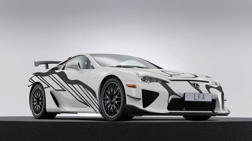 White Lexus LFA supercar with black graphics and a large rear wing on a grey studio platform in landscape.