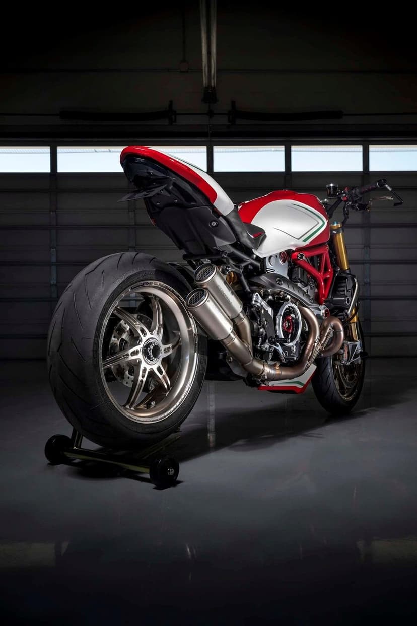 Red and white Ducati motorcycle showcasing a trellis frame and dual exhaust pipes in a dimly lit garage setting.