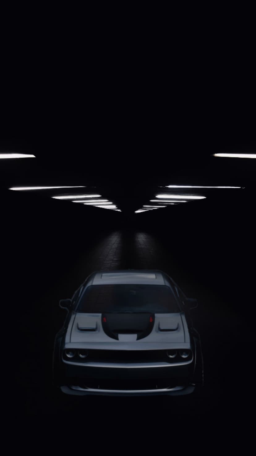 Black Dodge Challenger with glowing headlights parked under linear lights in a dark industrial tunnel.