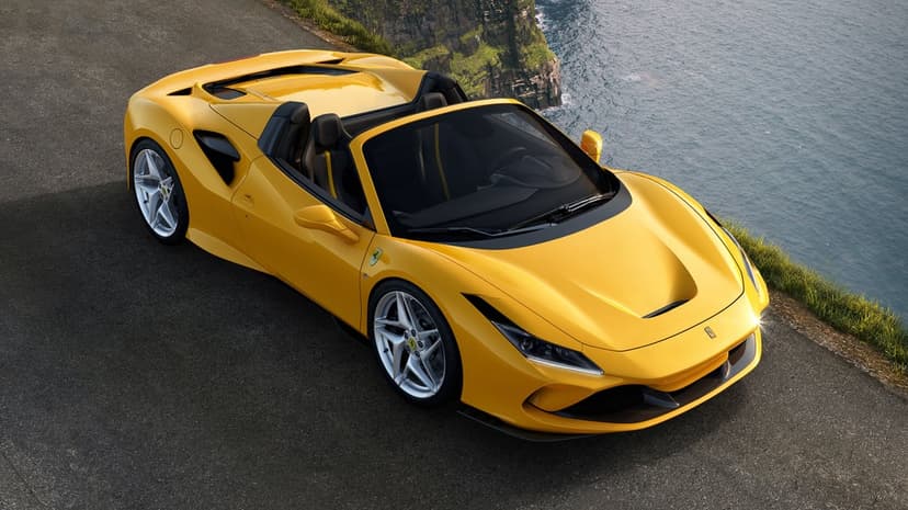 Yellow open-top supercar parked on an asphalt cliff road overlooking a blue ocean under bright daylight.