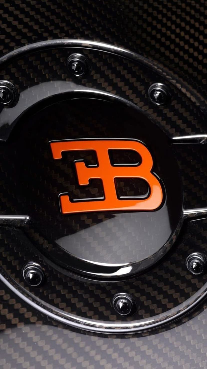 Bugatti EB logo in orange metallic finish centered on a textured black and grey carbon fiber weave pattern.