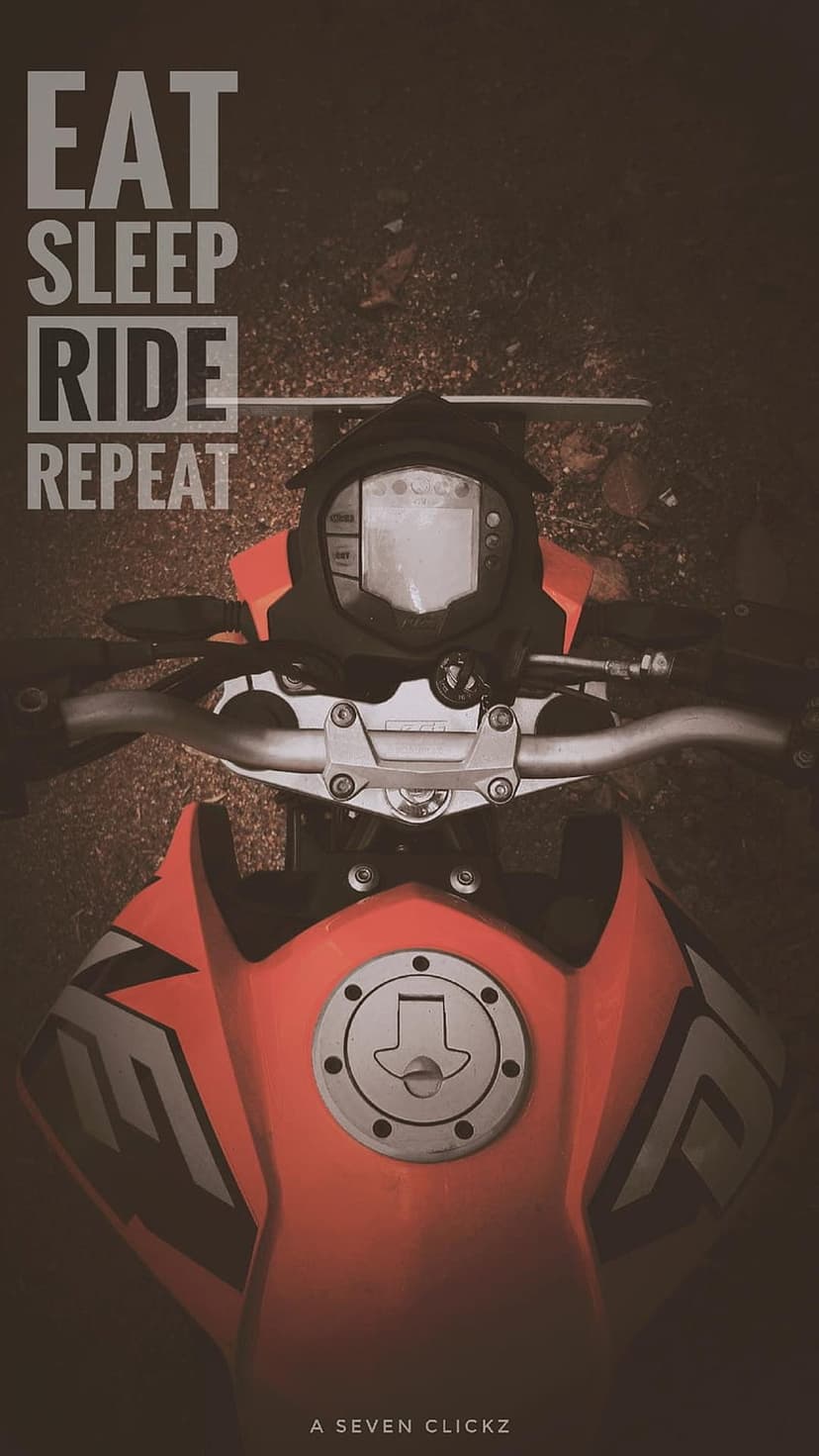 Orange motorcycle fuel tank and handlebars with bold white text on a dark and gritty earth background.