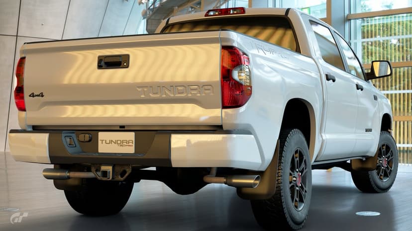 White Toyota Tundra TRD Pro rear view with dual exhausts and black wheels in a modern glass-walled showroom.