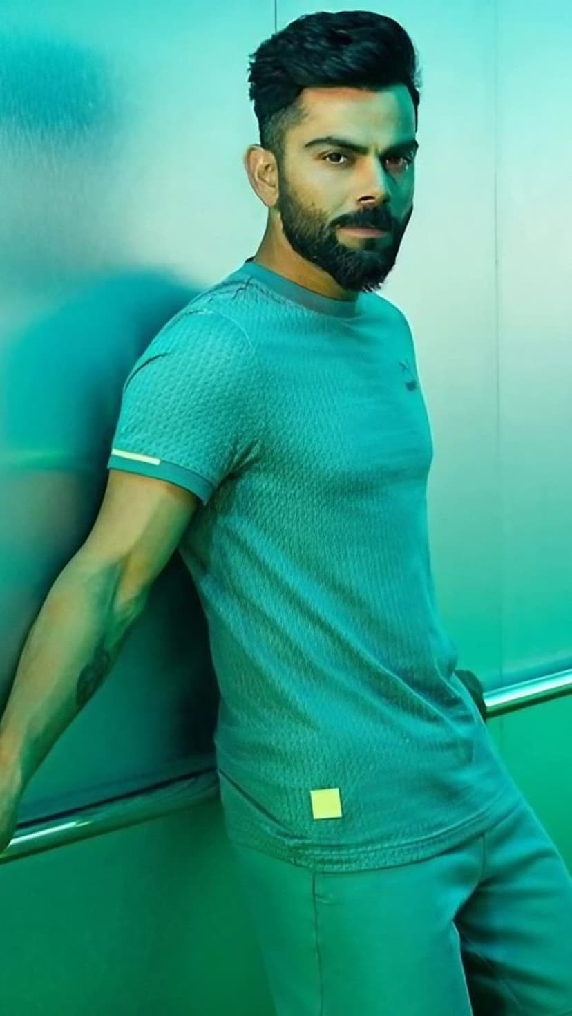 Virat Kohli leans against metal in teal athletic wear under vibrant green and turquoise neon studio lighting.