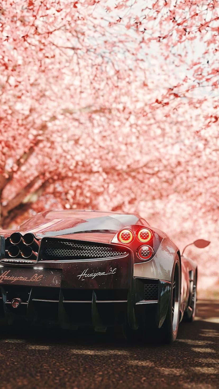 Pagani Huayra BC rear view with quad exhausts under pink cherry blossom trees in a soft spring light setting.