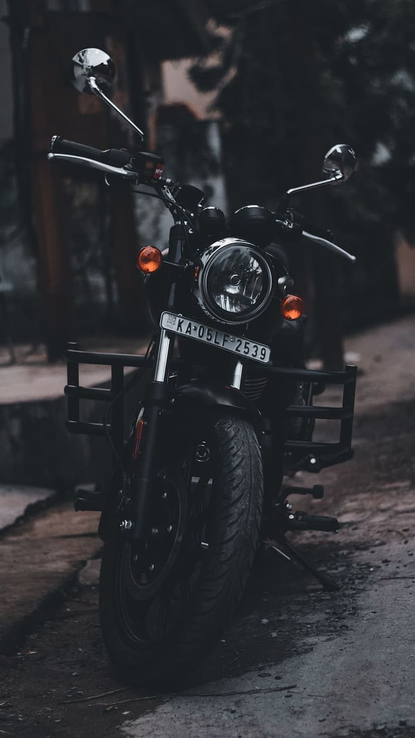 Black Royal Enfield motorcycle front view with a round headlight, amber turn signals, and polished chrome accents.
