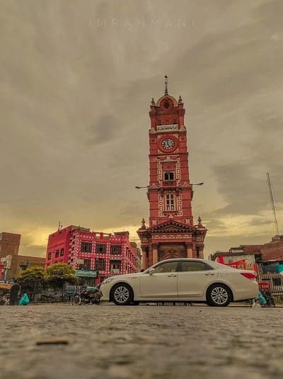 Iconic Clock Tower and White Sedan in Old City Square