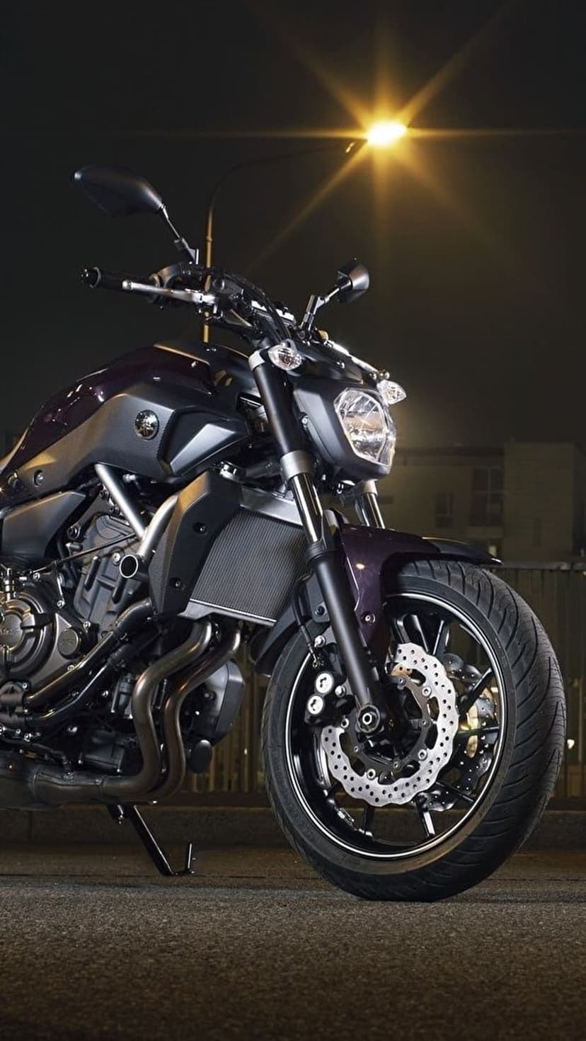 Yamaha motorcycle parked on asphalt under a glowing street lamp with a starburst effect and dark urban backdrop.