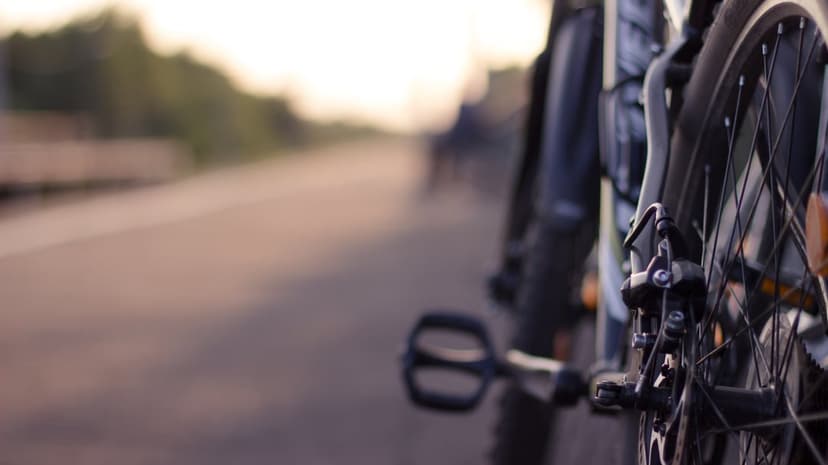 Bicycle rear wheel and pedal on an asphalt road during a golden sunset with a soft blurred background.