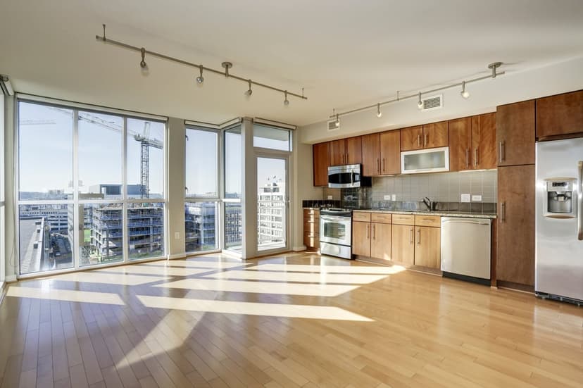 Modern kitchen with wood cabinets, steel appliances, and large windows overlooking a sprawling urban cityscape.