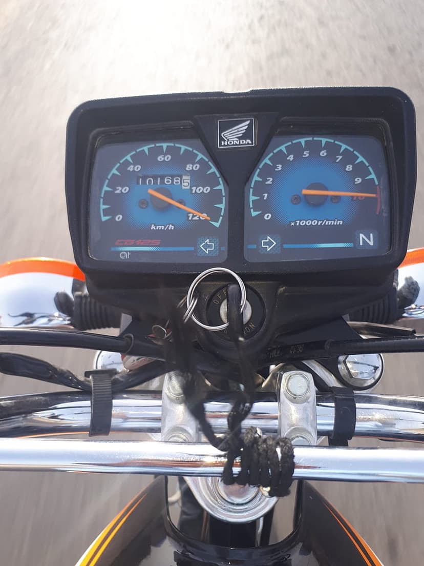 Honda motorcycle speedometer and tachometer gauges set between chrome handlebars with keys in the ignition switch.