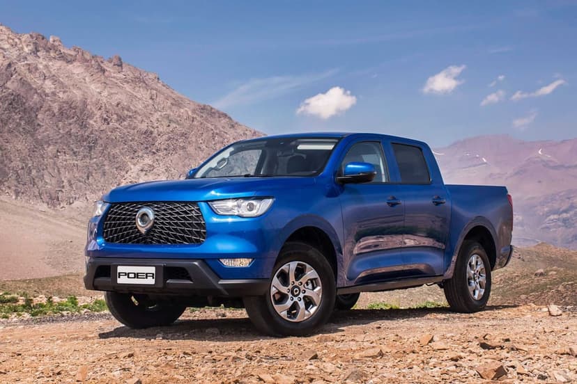 Blue GWM Poer pickup truck parked on a rocky mountain path under a clear blue sky with distant peaks.