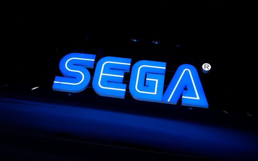 Illuminated SEGA logo sign in electric blue and white glowing brightly against a dark nocturnal background.